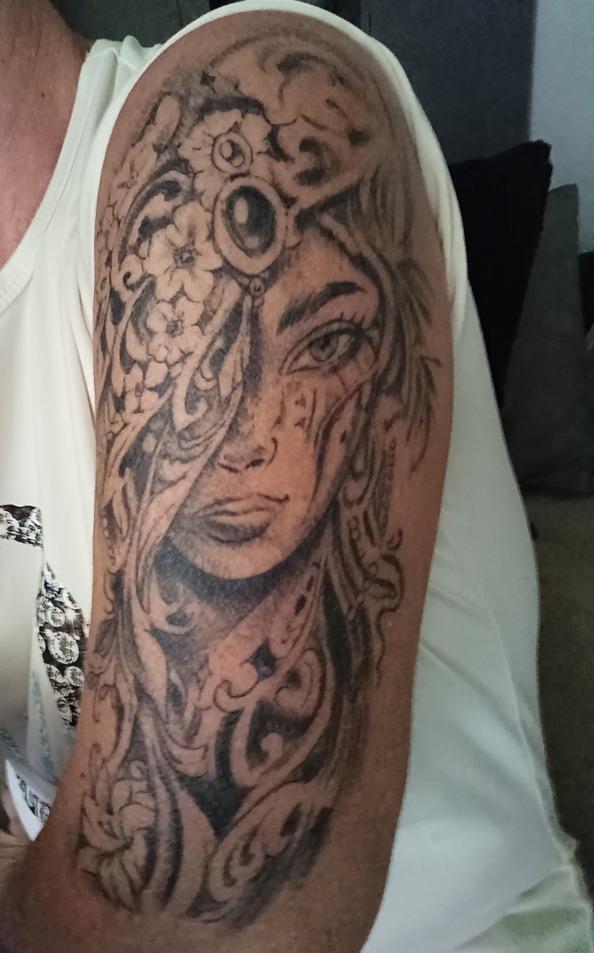 Vrouwenportret met sierlijke ornamenten getatoeëerd op een bovenarm